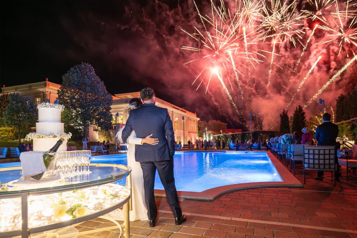 Sposi a bordo piscina che ammirano i fuochi d'artificio
